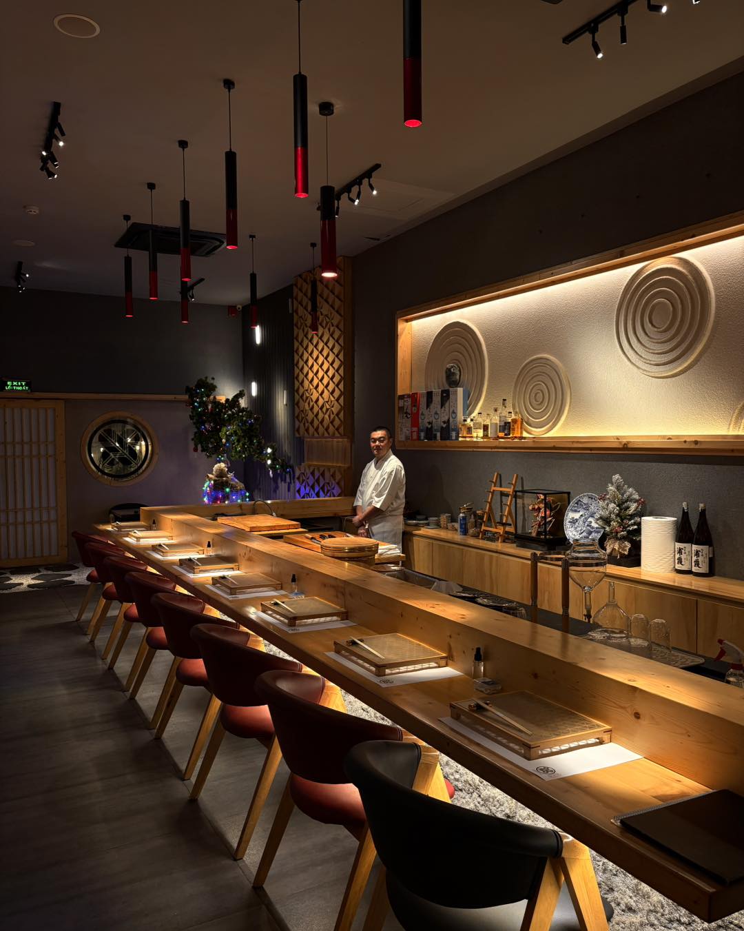The chef welcomes guests to Nishiyama's warm timber counter beneath the sand-pattern wall